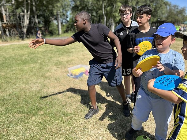 Kinder werfen Frisbeescheiben auf einer Wiese