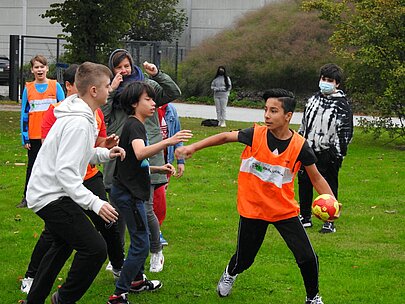 Schüler in Leibchen beim Völkerball auf der Wiese