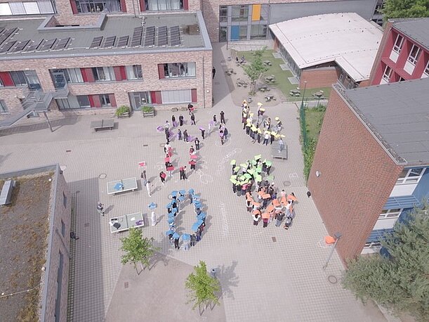7. Klassen bilden auf dem Schulhof Buchstaben, Luftaufnahme