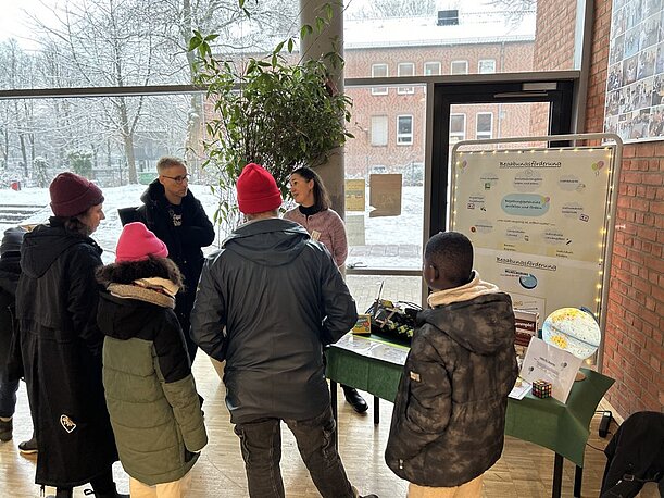 Besucherinnen und Besucher an einem Infostand im verschneiten Foyer beim Tag der offenen Tür