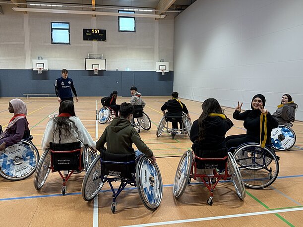 Jugendliche in Rollstühlen bilden einen Kreis in der Sporthalle
