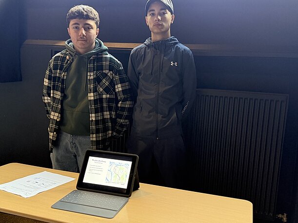 Zwei Schüler präsentieren ihr Profilprojekt mit Tablet am Tisch