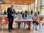 Gäste sitzen an einem blauen Tisch in der Kantine bei der Einweihung