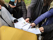 Jugendliche halten gemeinsam Briefe an einen gelben Briefkasten