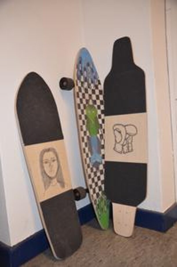 Drei selbst gestaltete Longboards lehnen an einer Wand