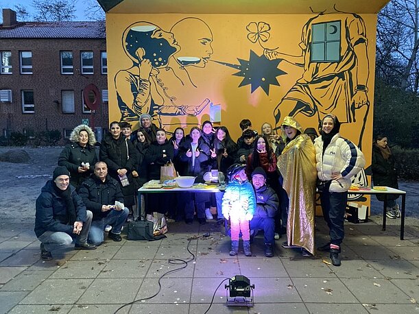 Klasse 8e posiert bei der Einweihung vor ihrem fertigen orangen Wandbild