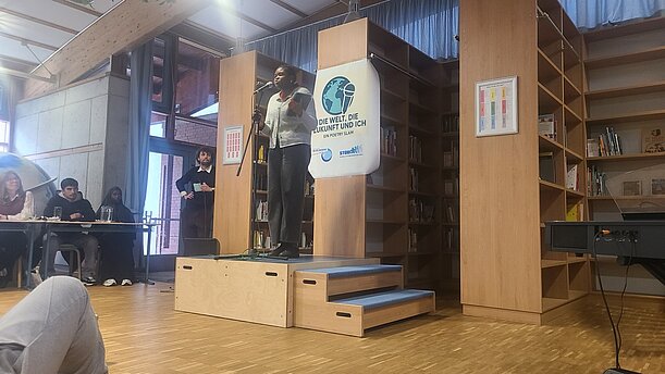 Poetry Slam in der Bibliothek: Vortragende auf dem Podest, Jury am Tisch