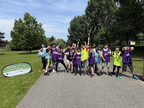 Jubelnde Jugendliche in Leibchen neben dem Parksport-Banner im Inselpark