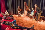 Kinder liegen auf roten Sitzsäcken beim Kinderkonzert mit Harfe und Cello in der Aula
