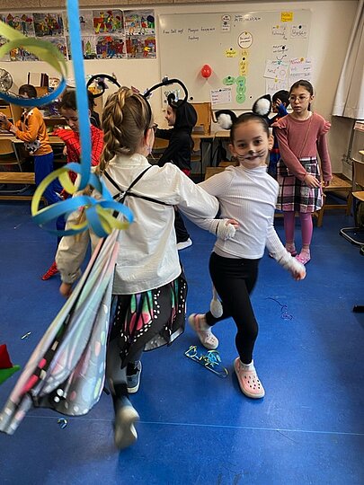 Verkleidete Kinder tanzen mit Luftschlangen bei der Faschingsfeier