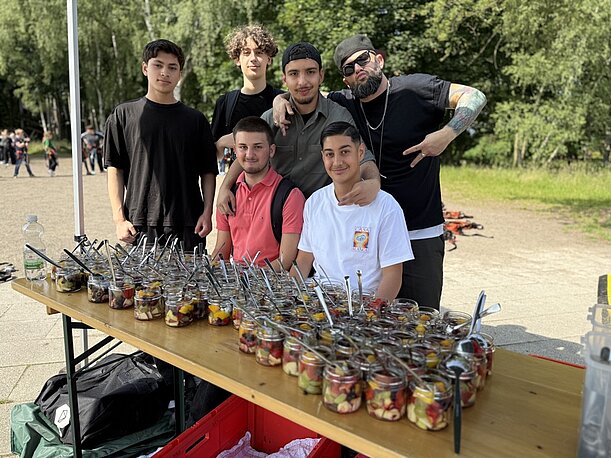 Gruppe junger Männer hinter einem Tisch mit Obstsalat-Gläsern