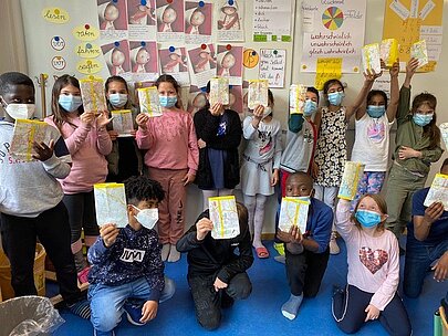 Grundschulkinder halten selbstgestaltete Blätter zum Ocean Day hoch
