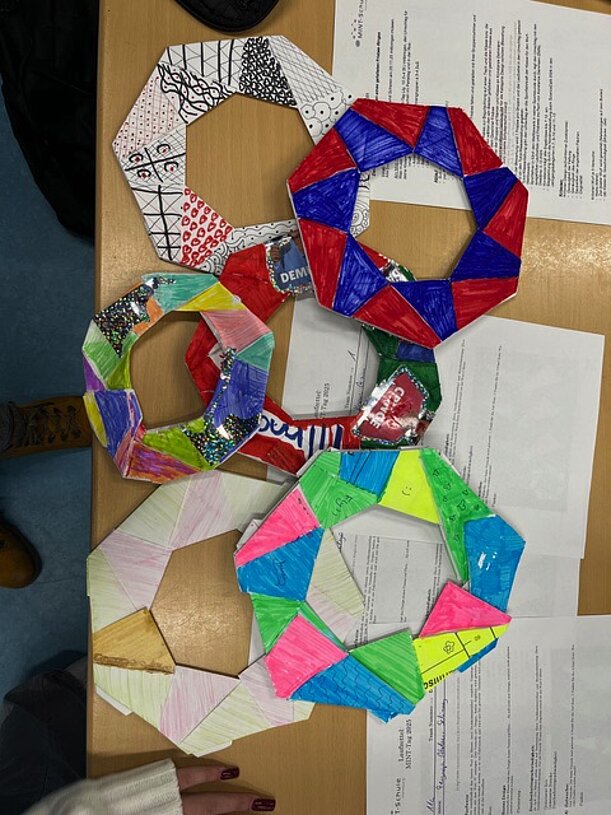 Mehrere bunt bemalte Papier-Frisbees liegen auf einem Tisch
