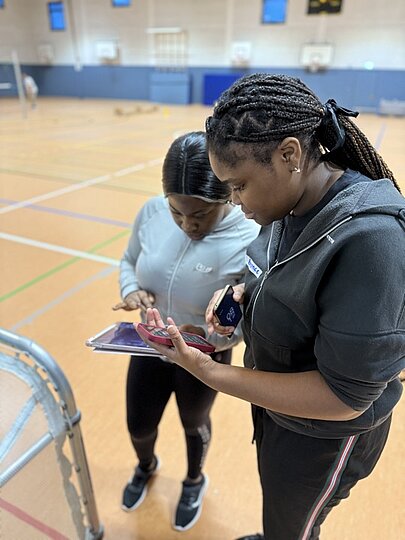 Zwei Schülerinnen schauen beim Sportfest gemeinsam auf ein Tablet