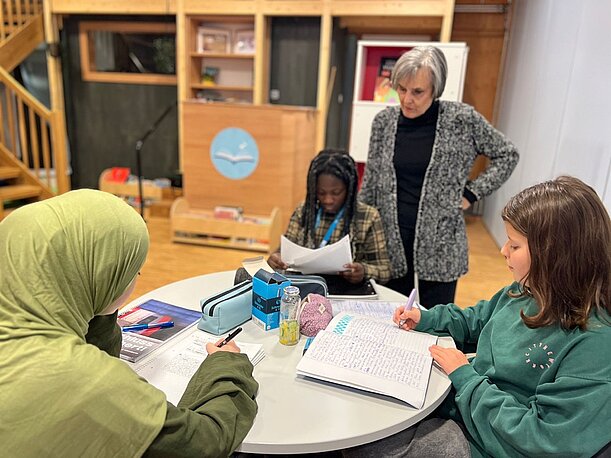 Schülerinnen arbeiten mit Lehrerin an Texten im Kurs Kreatives Schreiben