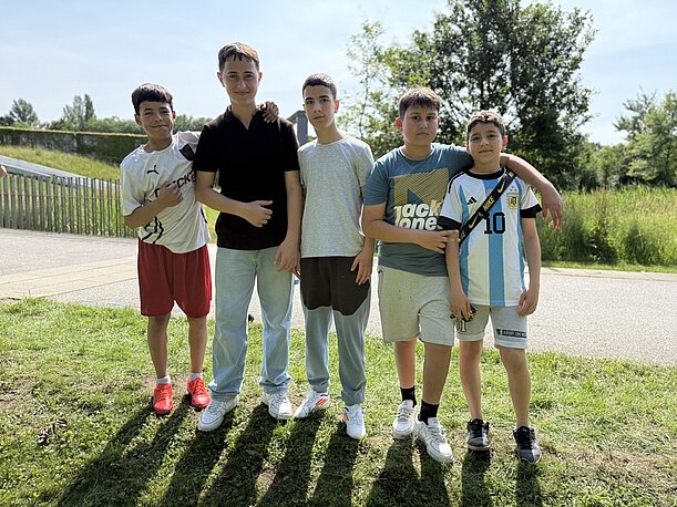Fünf Jungen posieren nebeneinander auf einem Weg im Park