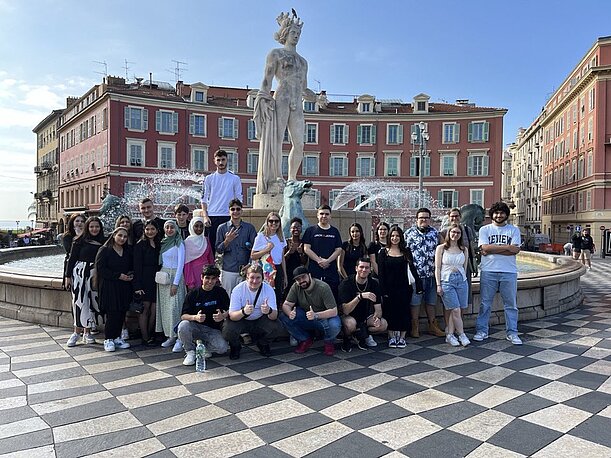 Gruppenfoto der Klasse vor einem Brunnen mit Statue in der Altstadt von Nizza