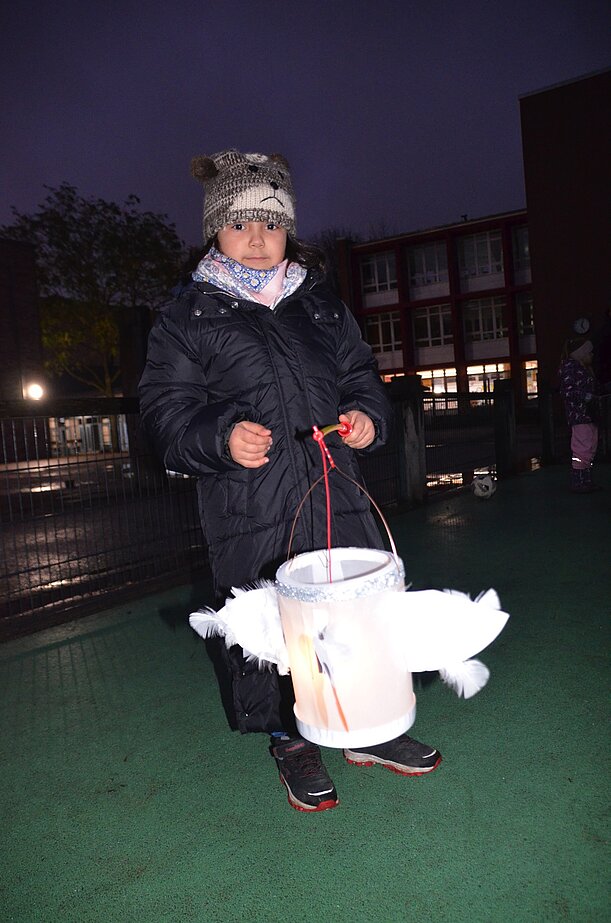 Kind mit weißer Vogel-Laterne beim abendlichen Laternenlauf