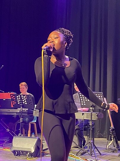 Sängerin in Schwarz singt vor Keyboarder auf blauer Bühne