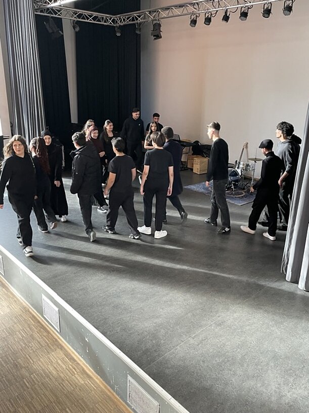 Gruppe in schwarzer Kleidung tanzt auf der Bühne der Kulturkantine