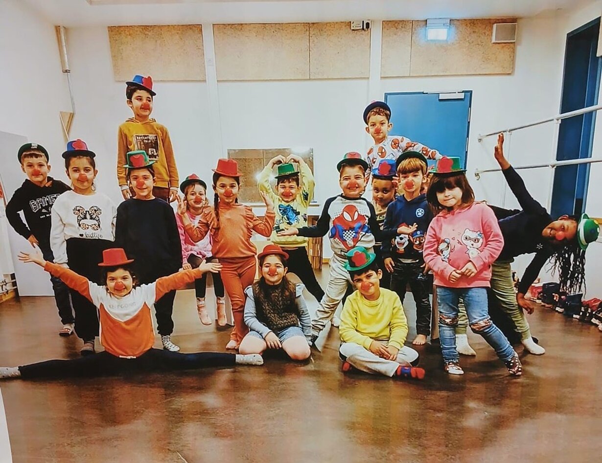 Verkleidete Vorschulkinder mit bunten Hüten posieren im Bewegungsraum
