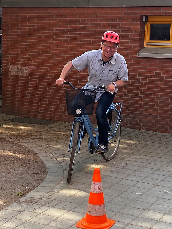 Verkehrspolizist fährt mit Fahrradhelm um einen Pylon