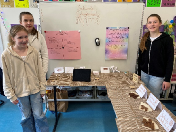 Schülerinnen an einem Projektstand mit Plakaten und Ausstellungsstücken