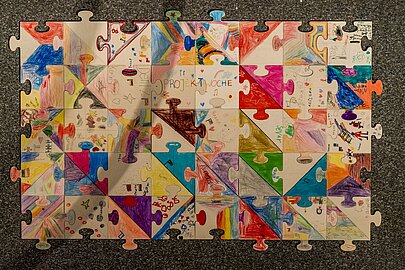 Großes Puzzle aus bunt bemalten Teilen von Grundschulkindern