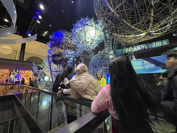 Jugendliche in einer Ausstellung mit leuchtenden Kugelskulpturen
