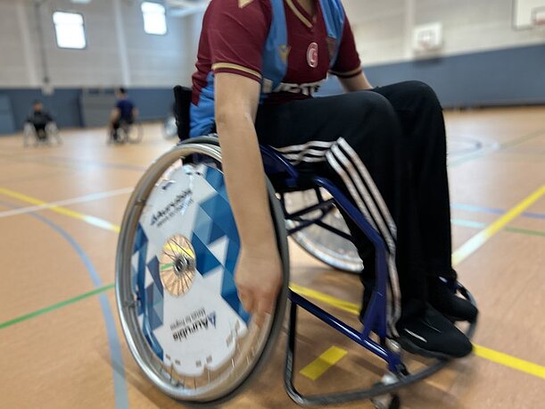 Yavuz fährt mit Sportrollstuhl durch die Sporthalle