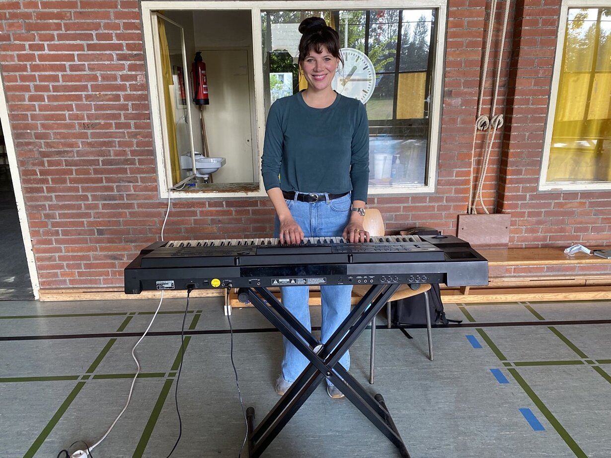 Musikpädagogin spielt am mobilen Keyboard in der Turnhalle