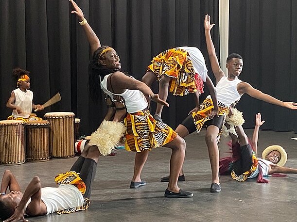 NAFSI-Tanzgruppe tanzt in bunten Kostümen mit Trommelbegleitung auf der Bühne