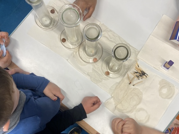 Kinderhände an Glasgefäßen mit Wasser bei einem Experiment von oben