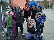 Verkleidete Schülerinnen und Schüler mit Masken vor dem Schulgebäude