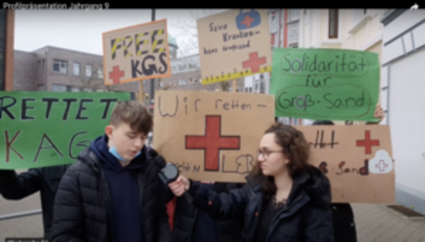 Interview vor Protestplakaten zur Rettung des Krankenhauses Groß-Sand