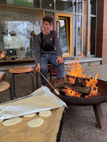 Jugendlicher backt Stockbrot an einer Feuerschale