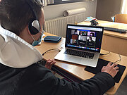 Schüler mit Kopfhörern im Videocall am Laptop beim MUT-Workshop