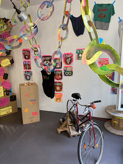 Installation mit Papierketten, Nachhaltigkeitsplakaten und Fahrrad in der Galerie