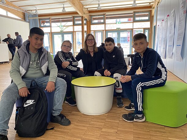 Schüler und Lehrerin sitzen an einem runden Tisch bei der Preisverleihung