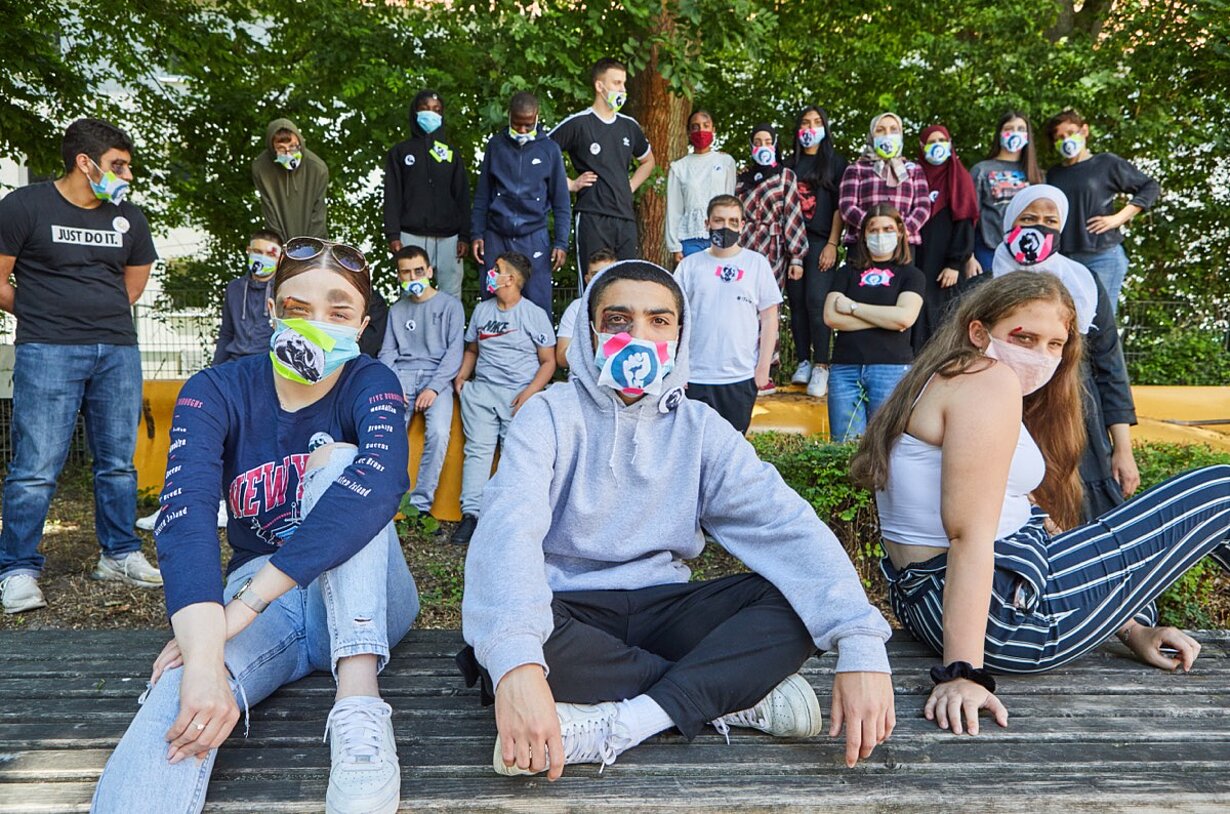 Gruppenbild der 10e, vorn sitzen drei Jugendliche mit gemusterten Masken