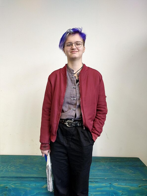 Luzie aus der 8a mit roter Jacke vor weißer Wand