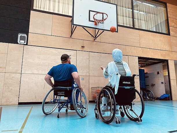 Basketballtrainer im Rollstuhl zeigt Schülerin den Positionswurf auf den Korb
