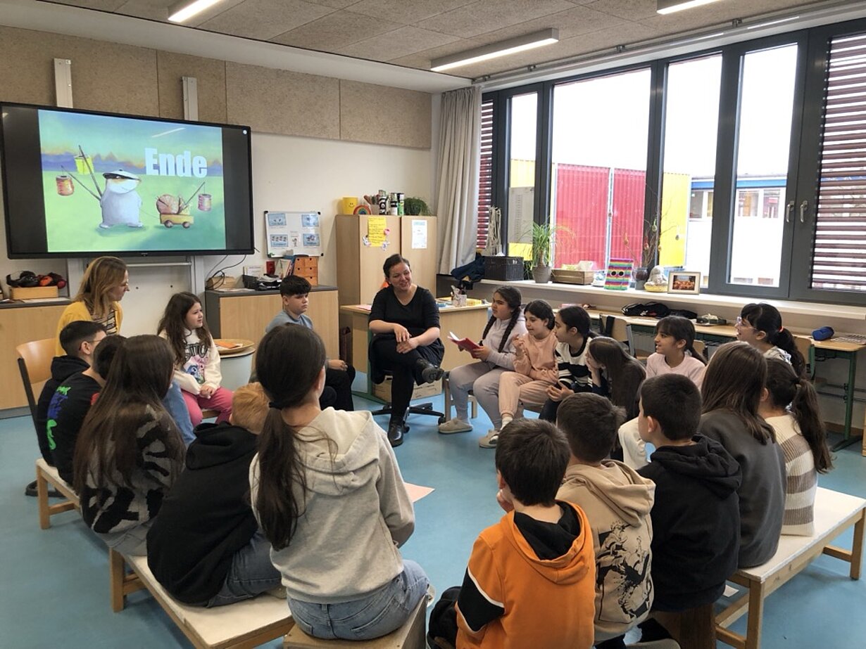 Klasse sitzt vor Bildschirm mit interaktiver Boardstory in der Grundschule am Perlstieg