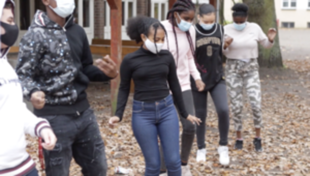 Jugendliche tanzen im Herbstlaub auf dem Schulhof