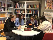 Schülerinnen arbeiten beim MINT-Tag gemeinsam an einem runden Tisch in der Bibliothek