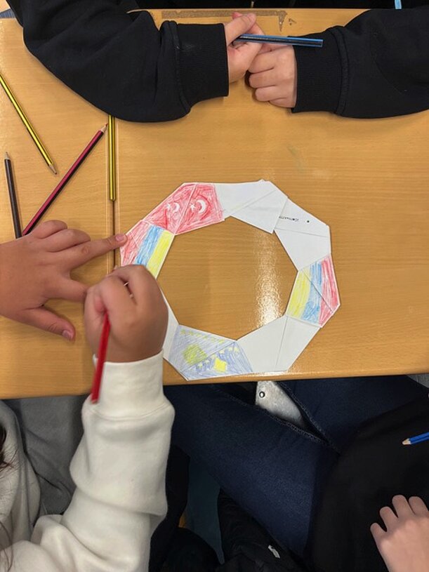 Schülerinnen und Schüler der 7a bemalen ein ringförmiges Papier-Frisbee