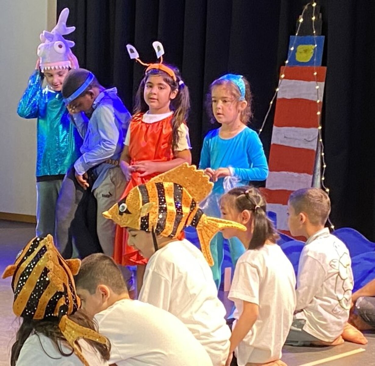 Vorschulkinder in Fisch- und Meerestierkostümen spielen Theater auf der Bühne