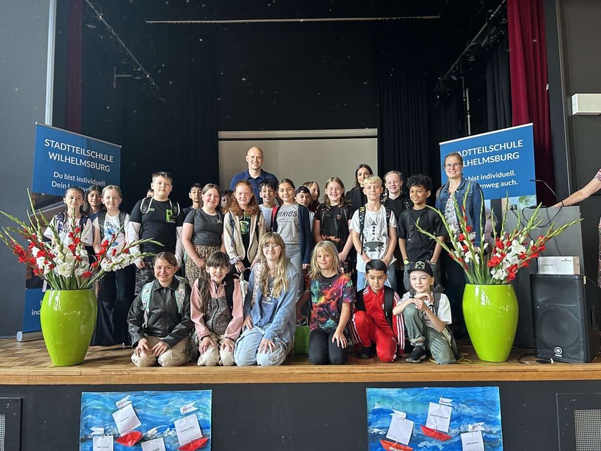 Klasse 5b bei der Einschulungsfeier auf der Bühne mit Blumenvasen
