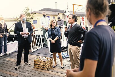 Gäste im Gespräch auf dem Ponton, vorn eine Holzkiste mit Flaschen