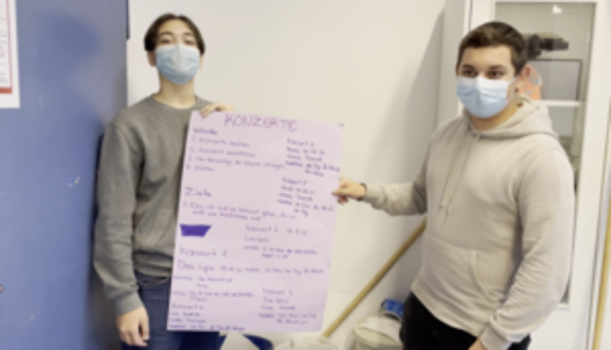 Zwei Schüler mit Plakat zur Profilarbeit Rund um die Bühne